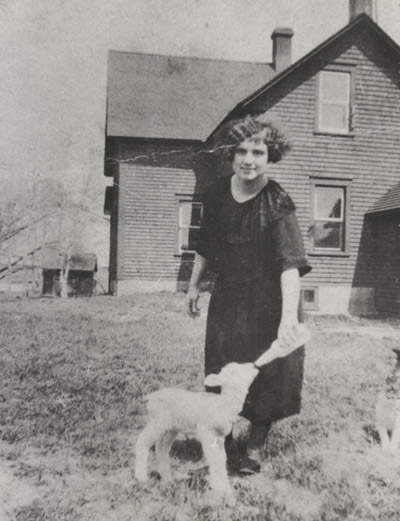 Jeune femme donnant à boire à un agneau au Manoir Ross